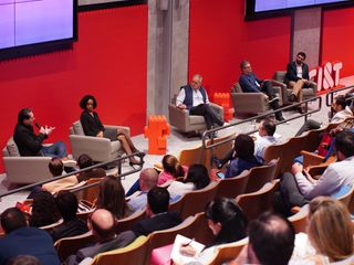 An a filled auditorium watching 5 speakers on stage including CI&T EVP Partner of Operations, Solange Sobral, and CI&T CSO Bob Wollheim