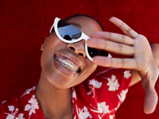 Close-up of smiling woman with braces with her hand up