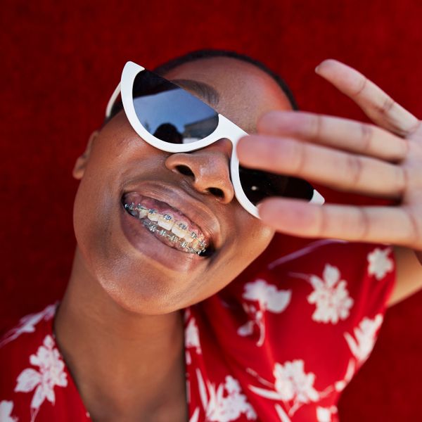 Close-up of smiling woman with braces with her hand up