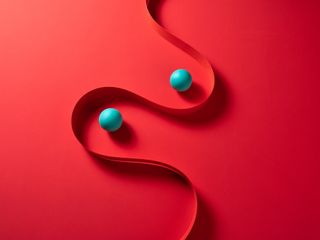 Curved paper stripe and spheres on red colored background