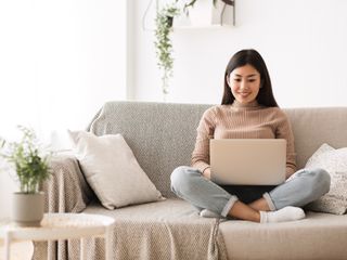 Girl sitting on a couch using a laptop