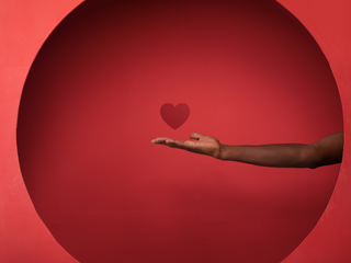 Hand in a red background with a heart icon above it