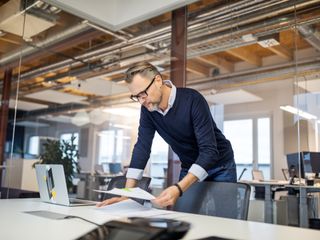 Man standing in office reading a document