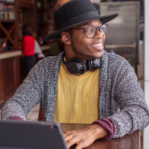 Man with digital tablet in airport bar smiles as he looks out the window