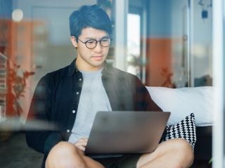 Man working with a laptop in the bedroom at home