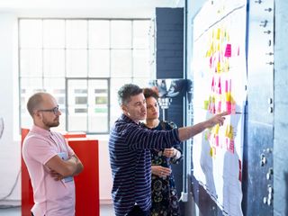 Men and woman looking at colorful adhensive notes on whiteboard