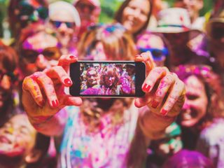People dirty on powder paint taking a selfie together at a party