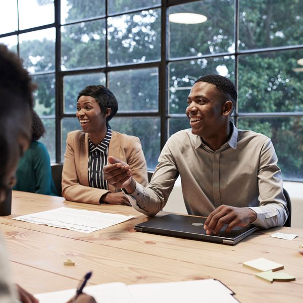 Smiling business colleagues sitting in conference room during office meeting at workplace