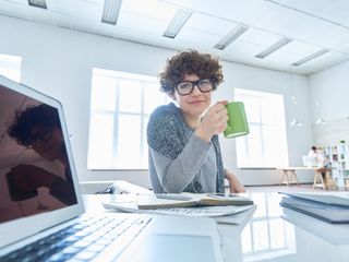 Woman drinking coffee at desk 