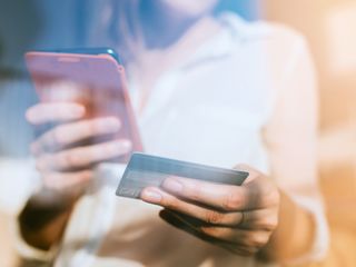 Woman shopping online with smartphone and credit card on hand