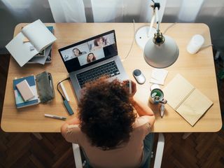 Woman sitting at home and talking in a meeting using her laptop