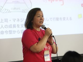 Woman talking in front of the room holding a microphone