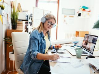 Woman with a headphone working from home on laptop